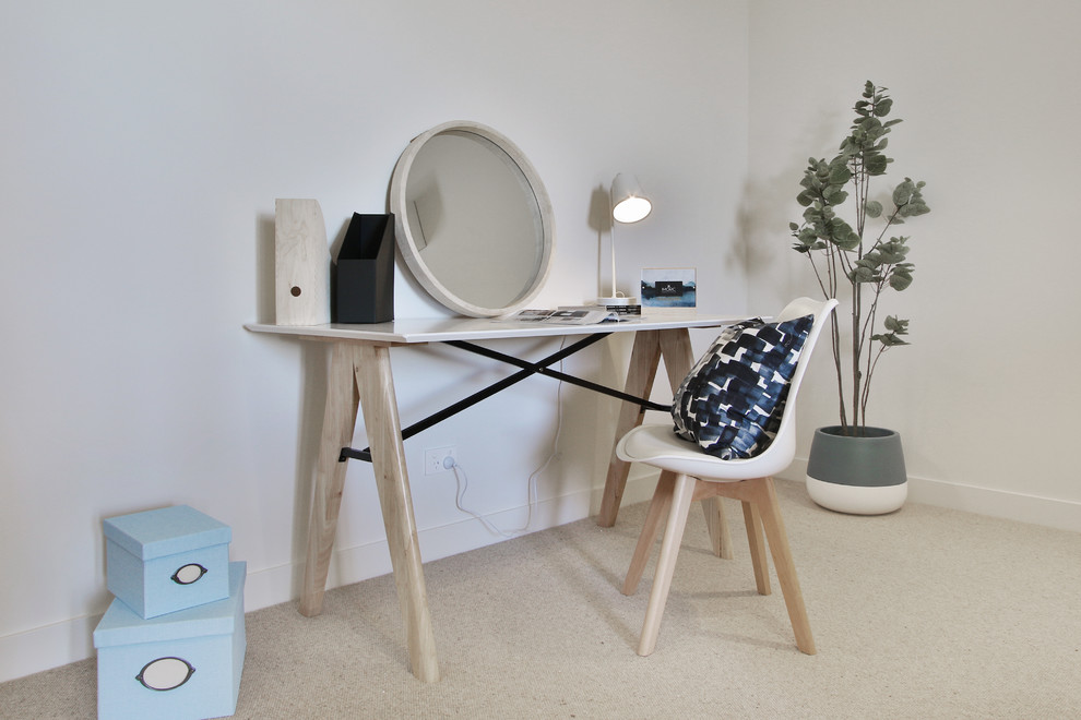 Inspiration för små minimalistiska hemmabibliotek, med vita väggar, heltäckningsmatta, ett fristående skrivbord och beiget golv