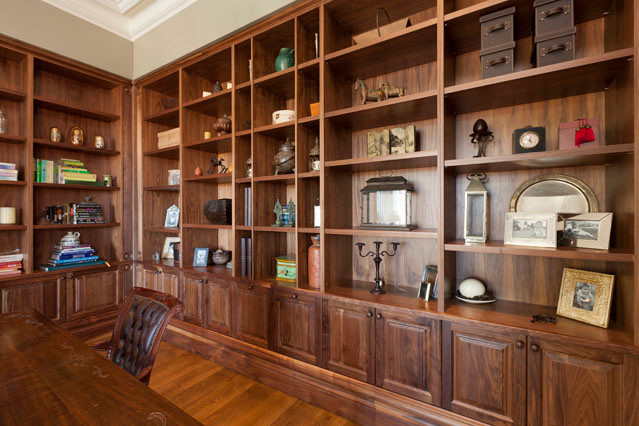 Foto de despacho actual sin chimenea con biblioteca, paredes beige, suelo de madera en tonos medios y escritorio independiente