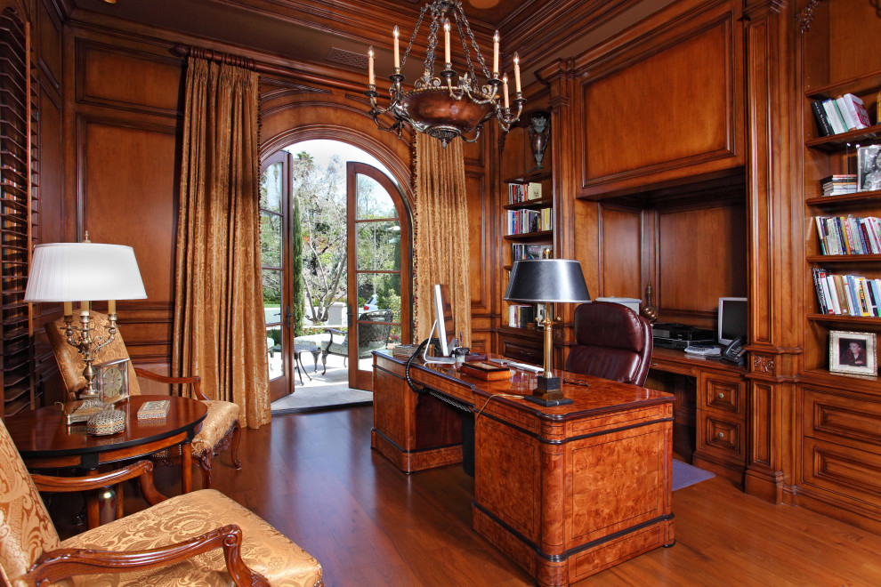 Großes Mediterranes Lesezimmer mit brauner Wandfarbe, dunklem Holzboden, freistehendem Schreibtisch und braunem Boden in Orange County