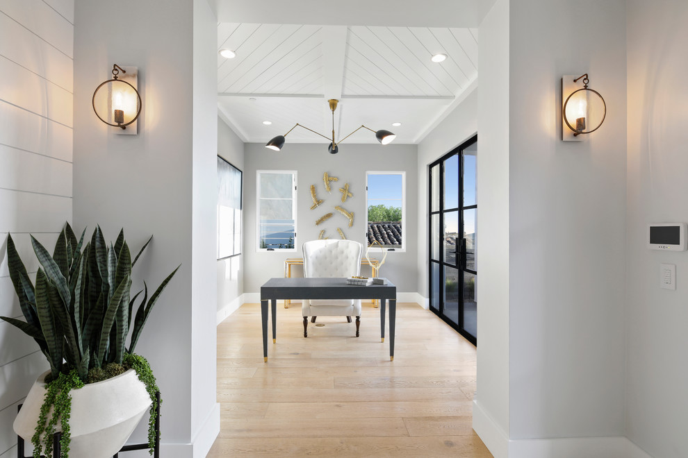 Ejemplo de despacho costero con paredes grises, suelo de madera clara, escritorio independiente y suelo beige