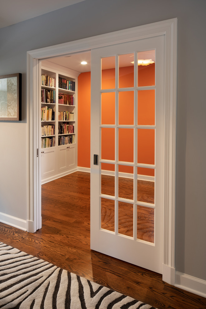 Idéer för ett litet klassiskt hemmabibliotek, med orange väggar, mellanmörkt trägolv och brunt golv