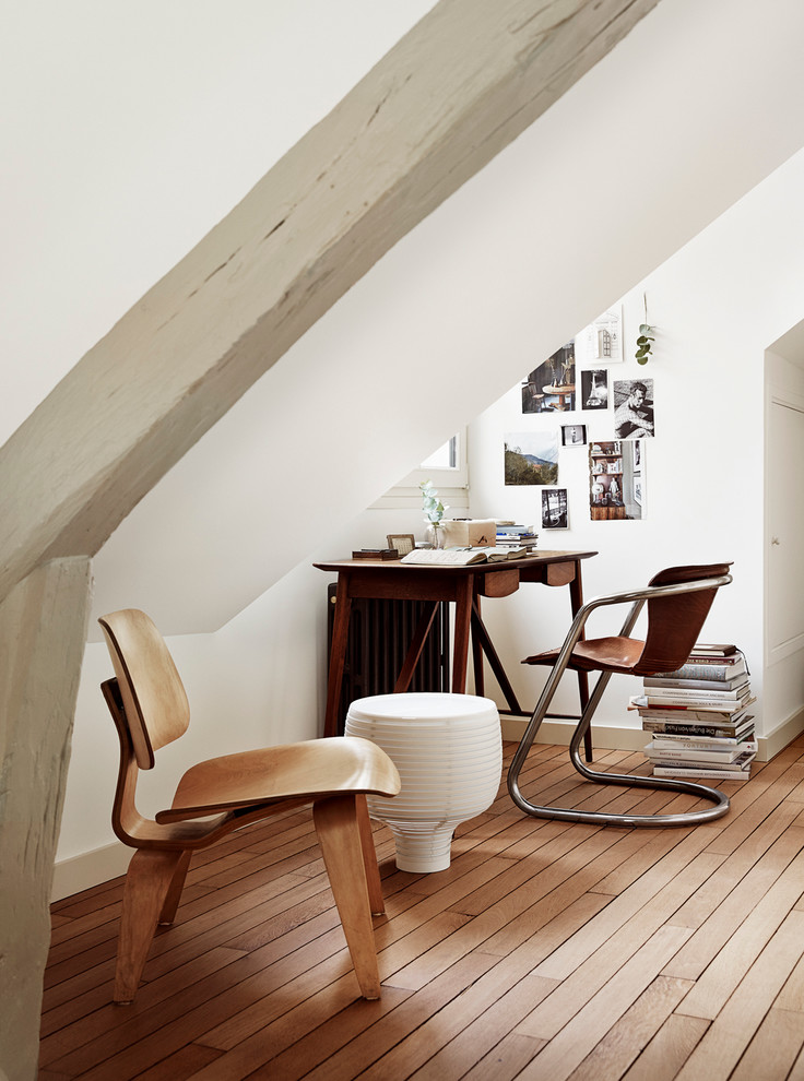 Kleines Nordisches Arbeitszimmer ohne Kamin mit weißer Wandfarbe, braunem Holzboden, freistehendem Schreibtisch und Arbeitsplatz in Paris