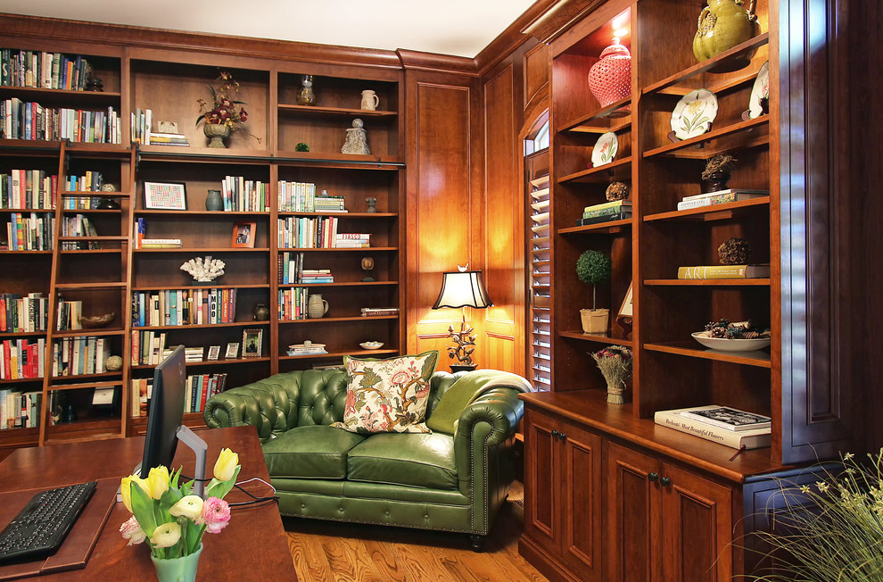 Foto de despacho tradicional de tamaño medio con biblioteca, suelo de madera en tonos medios y escritorio independiente