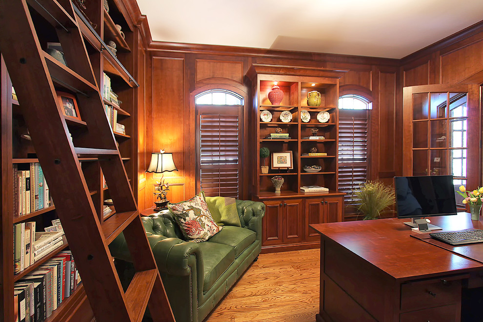 На фото: домашняя библиотека среднего размера в классическом стиле с паркетным полом среднего тона и отдельно стоящим рабочим столом с