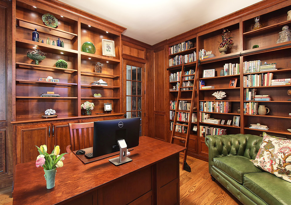 Modelo de despacho tradicional de tamaño medio con biblioteca, suelo de madera en tonos medios y escritorio independiente