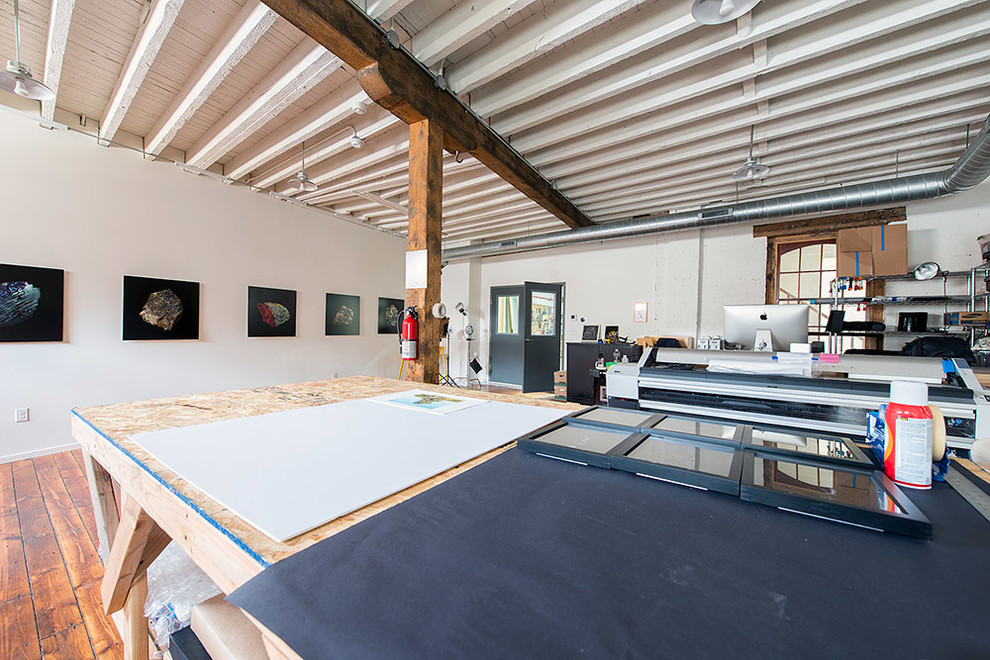Großes Industrial Arbeitszimmer ohne Kamin mit Studio, weißer Wandfarbe, hellem Holzboden und freistehendem Schreibtisch in Philadelphia