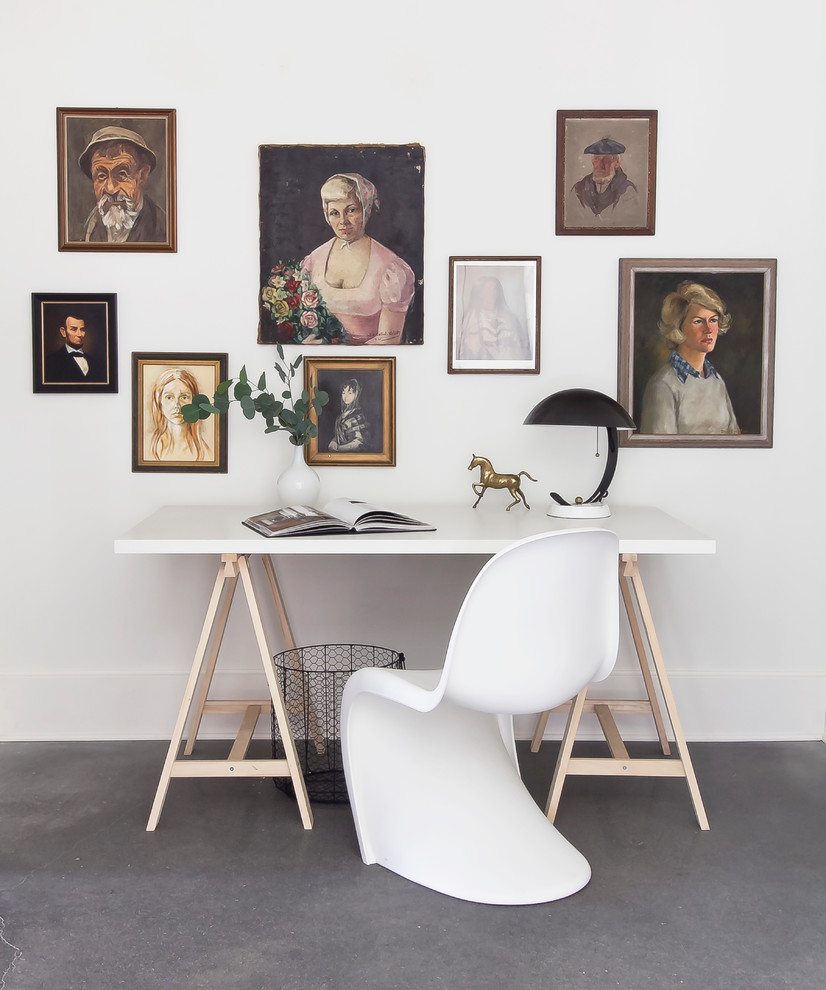Foto på ett litet minimalistiskt arbetsrum, med vita väggar, betonggolv och ett fristående skrivbord
