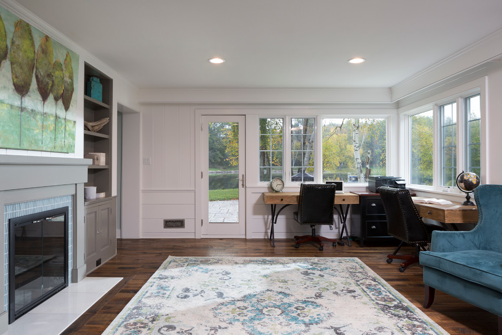 Large classic home studio in Milwaukee with white walls, medium hardwood flooring, a standard fireplace, a tiled fireplace surround and a freestanding desk.