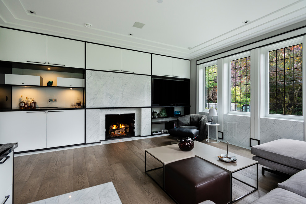This is an example of a large world-inspired study in Vancouver with grey walls, medium hardwood flooring, a standard fireplace, a stone fireplace surround, a built-in desk and brown floors.