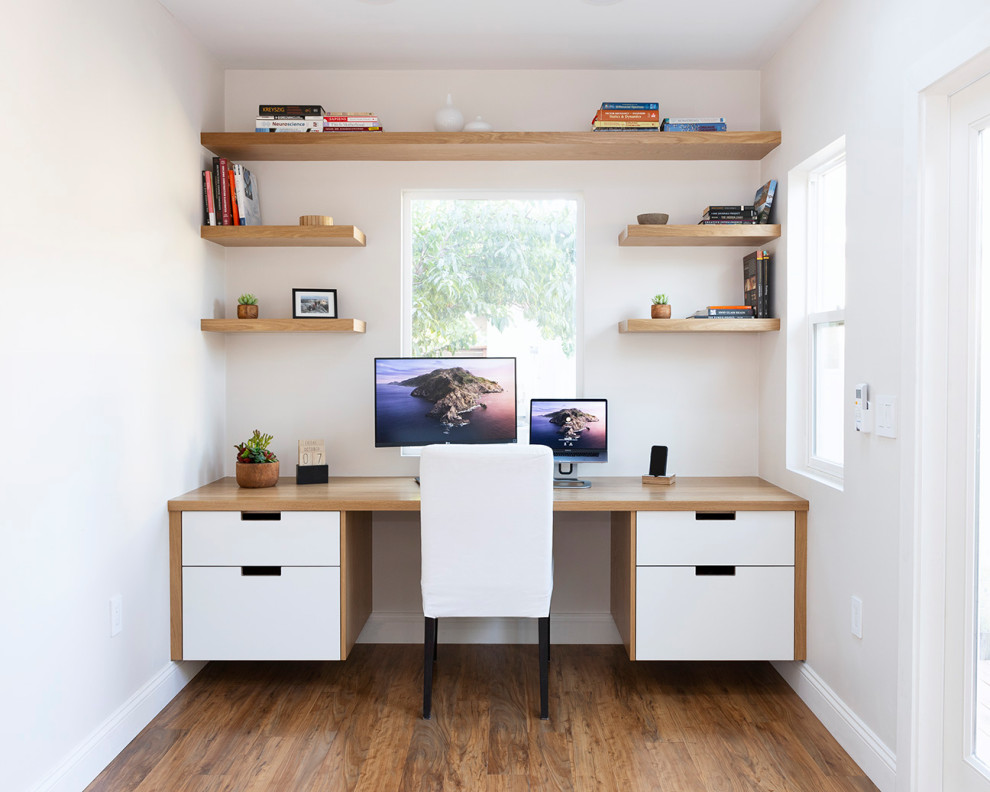 Inspiration for a small modern home studio in San Francisco with white walls, laminate floors, no fireplace, a built-in desk, brown floors and a vaulted ceiling.