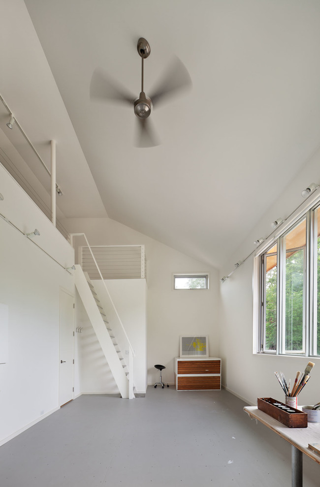 На фото: домашняя мастерская в современном стиле с белыми стенами и отдельно стоящим рабочим столом с