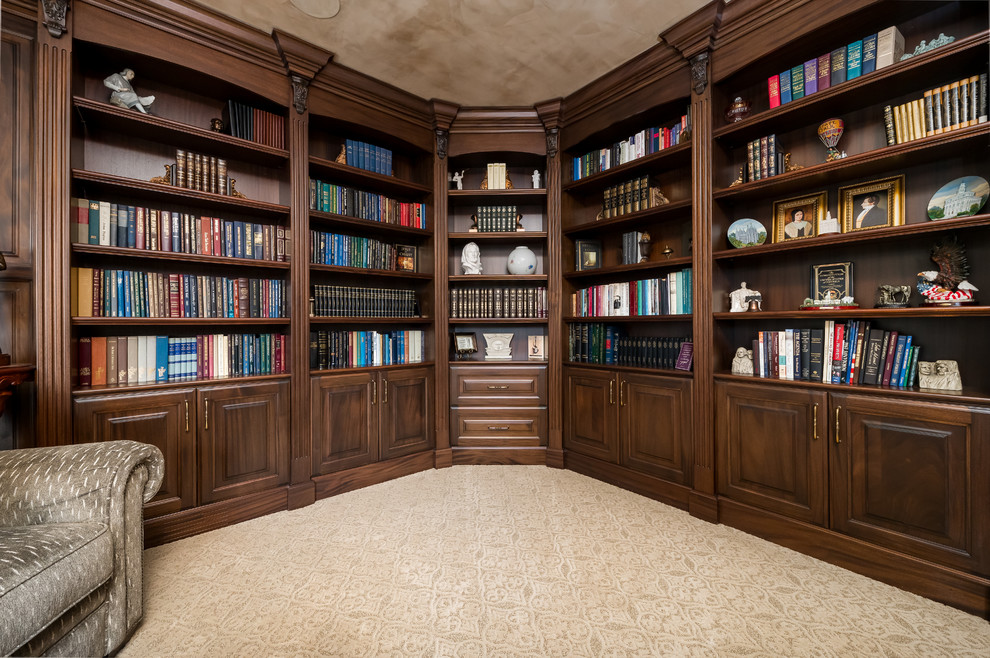 Inredning av ett klassiskt mellanstort arbetsrum, med ett bibliotek, bruna väggar, heltäckningsmatta och beiget golv