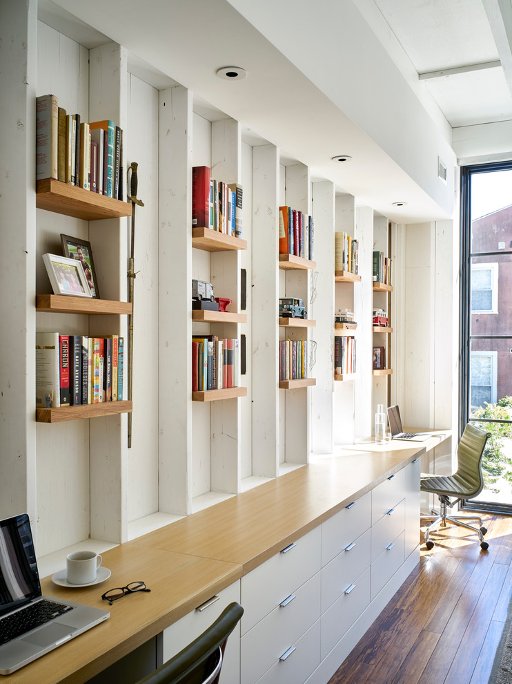 Inspiration för moderna hemmabibliotek, med vita väggar, bambugolv och ett inbyggt skrivbord