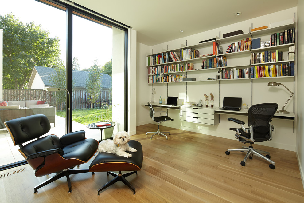Idéer för ett modernt arbetsrum, med vita väggar, mellanmörkt trägolv och ett inbyggt skrivbord