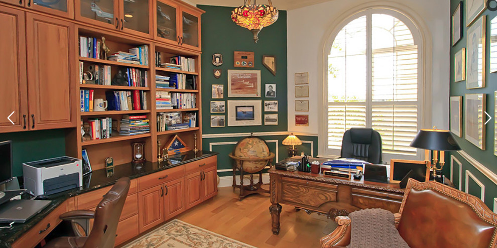 Foto di uno studio mediterraneo di medie dimensioni con libreria, pareti verdi, pavimento in legno massello medio, nessun camino, scrivania incassata e pavimento marrone