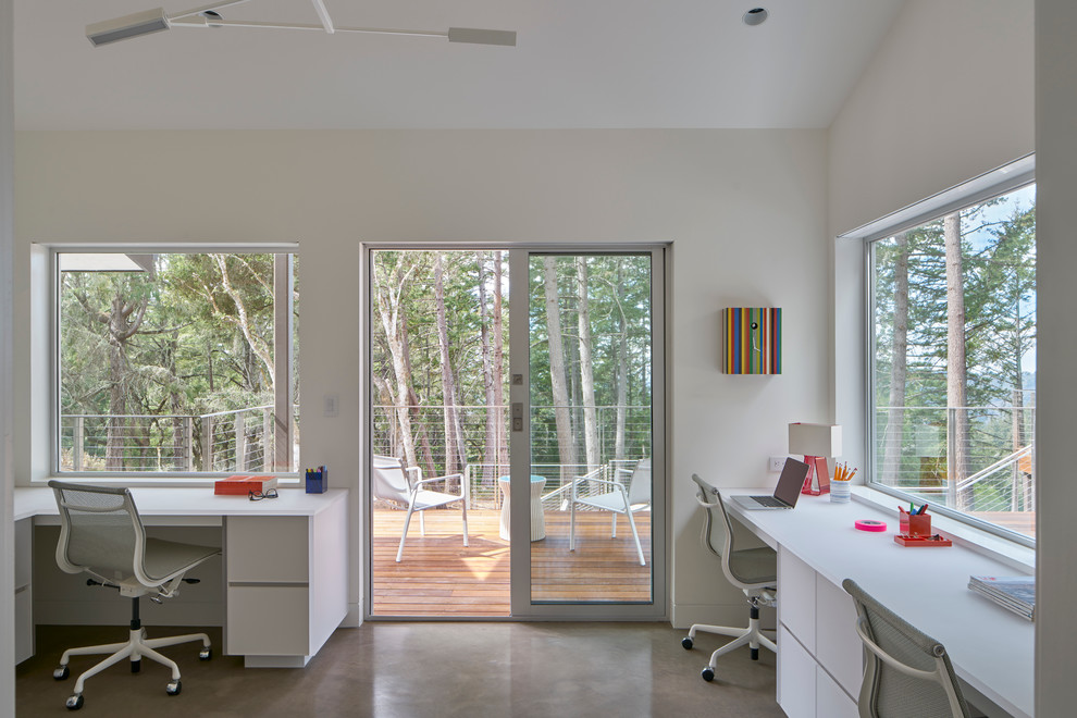 Cette image montre un bureau design de taille moyenne avec un mur blanc, sol en béton ciré, aucune cheminée et un bureau intégré.