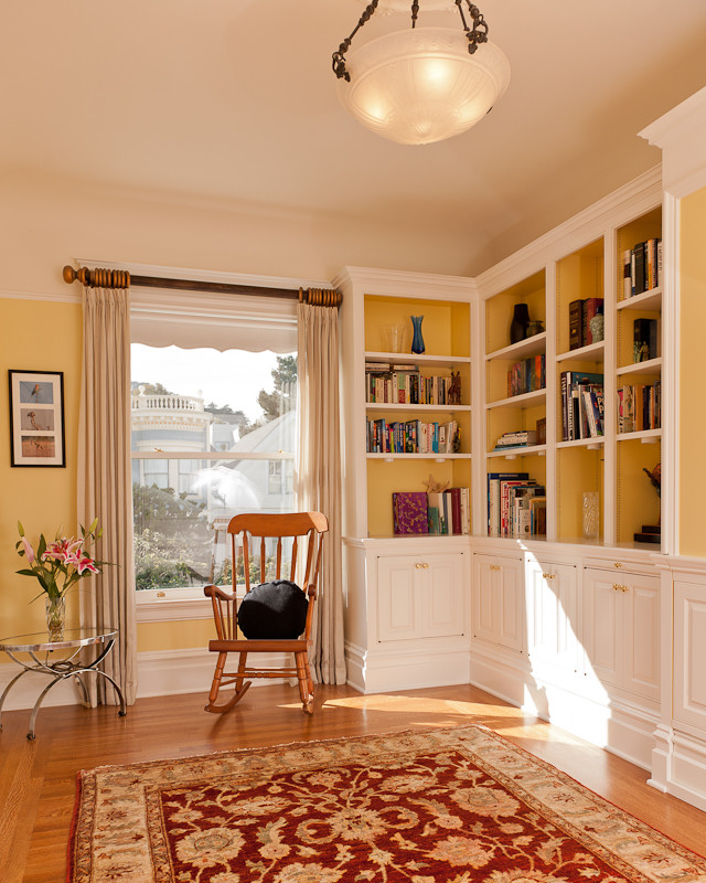 Cette photo montre un bureau chic de taille moyenne avec un mur jaune, un sol en bois brun, aucune cheminée et un bureau indépendant.