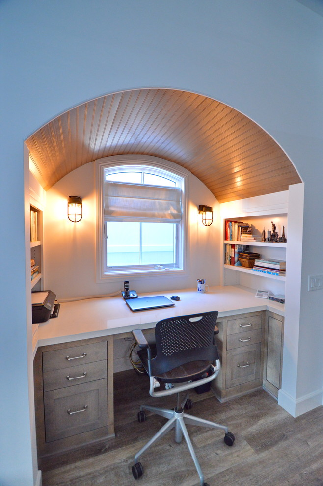 На фото: рабочее место в морском стиле с белыми стенами, светлым паркетным полом, встроенным рабочим столом и коричневым полом без камина