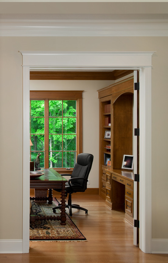 Foto di un ampio ufficio chic con pareti beige, pavimento in legno massello medio, scrivania autoportante e pavimento marrone