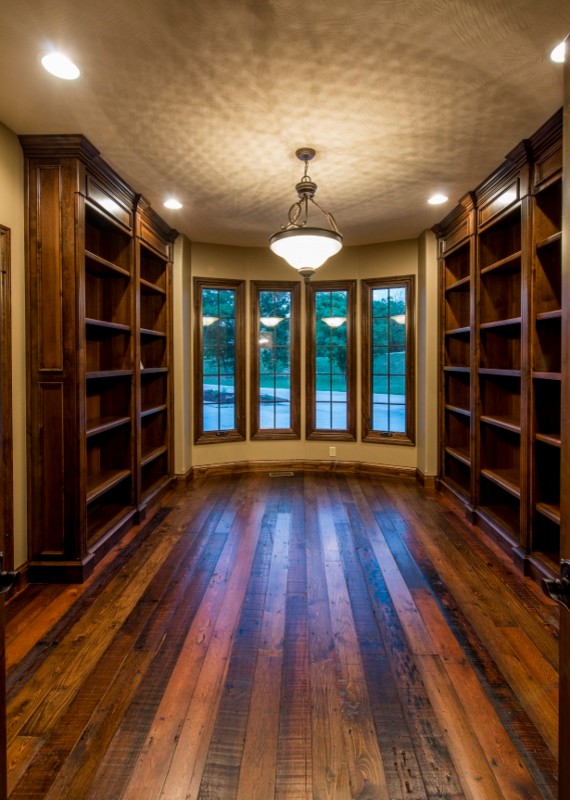 Ejemplo de despacho clásico grande sin chimenea con biblioteca, paredes beige y suelo de madera oscura