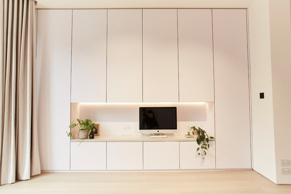 Idée de décoration pour un petit bureau minimaliste avec un mur blanc, parquet clair, un bureau intégré et un sol beige.