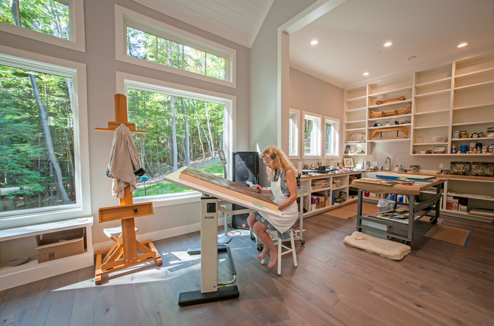 Cette photo montre un très grand bureau atelier nature avec un mur gris, un sol en bois brun, un bureau indépendant et un sol gris.