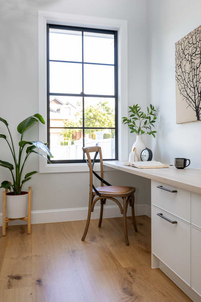 Modelo de despacho clásico renovado con paredes grises, suelo de madera en tonos medios, escritorio empotrado y suelo marrón