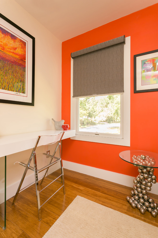 Inredning av ett eklektiskt mellanstort hemmastudio, med orange väggar, mellanmörkt trägolv, ett fristående skrivbord och brunt golv