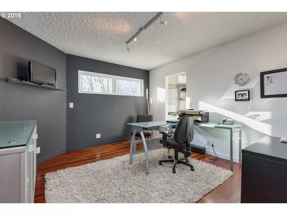 Mid-sized trendy freestanding desk medium tone wood floor and brown floor home office photo in Portland with blue walls