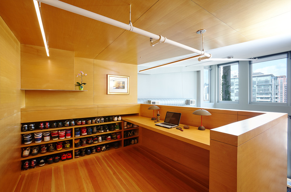 Aménagement d'un bureau moderne avec un sol en bois brun et un bureau intégré.