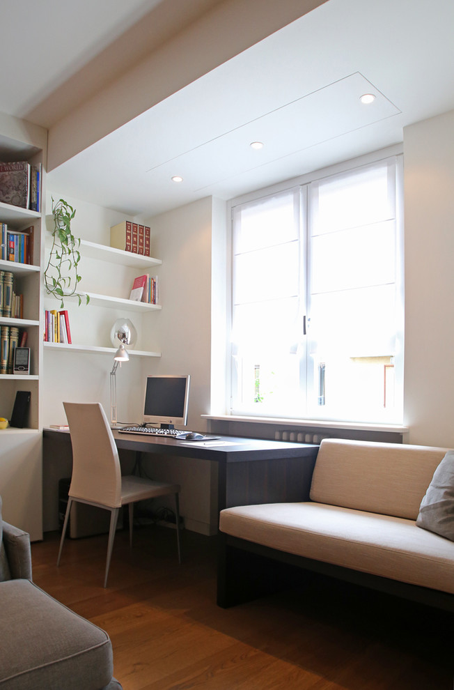 Photo of a small contemporary study in Milan with white walls, medium hardwood flooring and a built-in desk.
