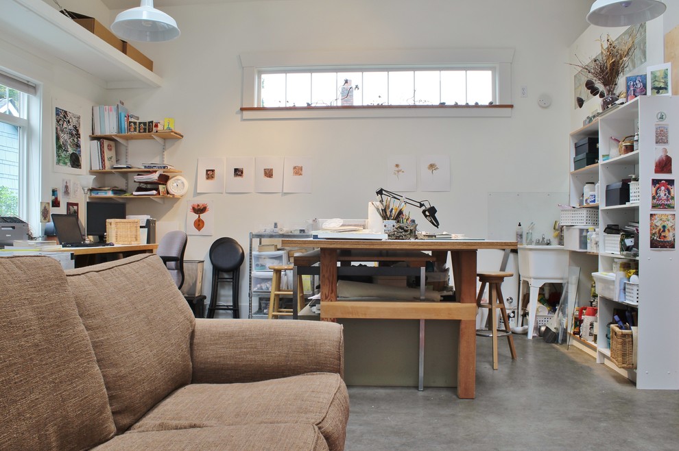 Idee per un atelier minimal con pareti bianche, pavimento in cemento e scrivania autoportante