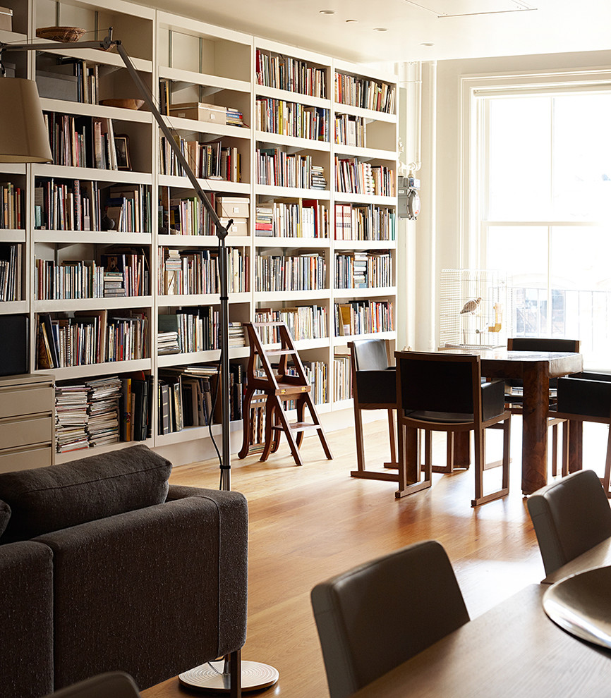 Mittelgroßes Industrial Lesezimmer mit weißer Wandfarbe, hellem Holzboden, freistehendem Schreibtisch und braunem Boden in New York