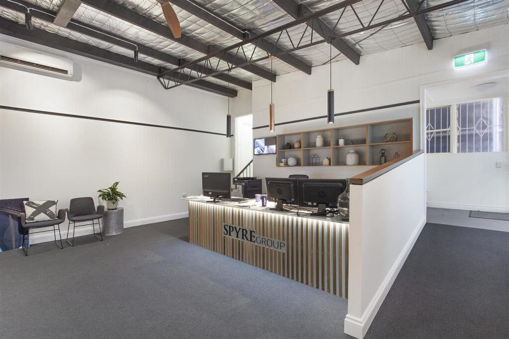 Aménagement d'un grand bureau moderne avec un mur blanc, moquette, un bureau intégré et un sol gris.