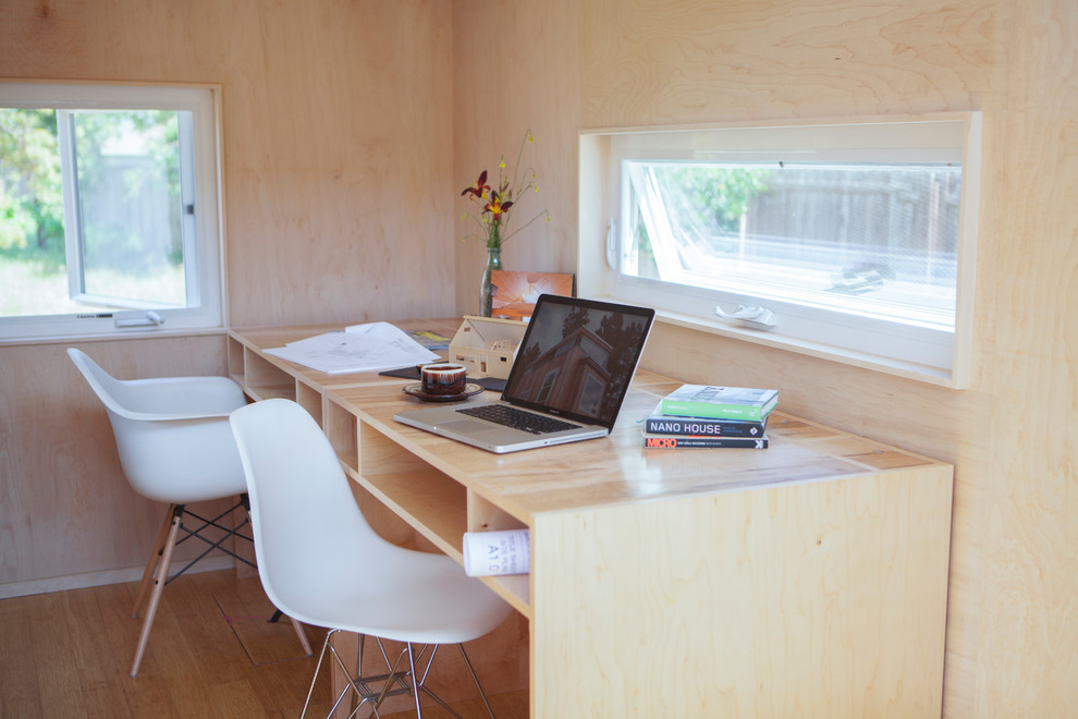 This is an example of a small modern home studio in Santa Barbara with no fireplace, a built-in desk and bamboo flooring.