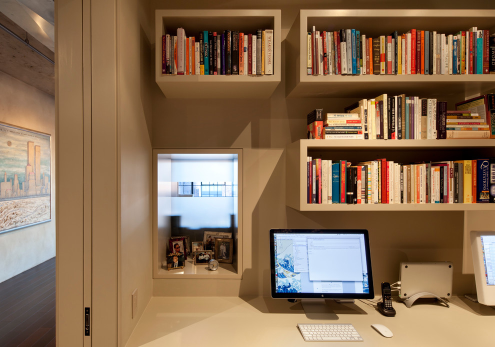 Idéer för ett litet industriellt hemmabibliotek, med vita väggar, mörkt trägolv och ett inbyggt skrivbord
