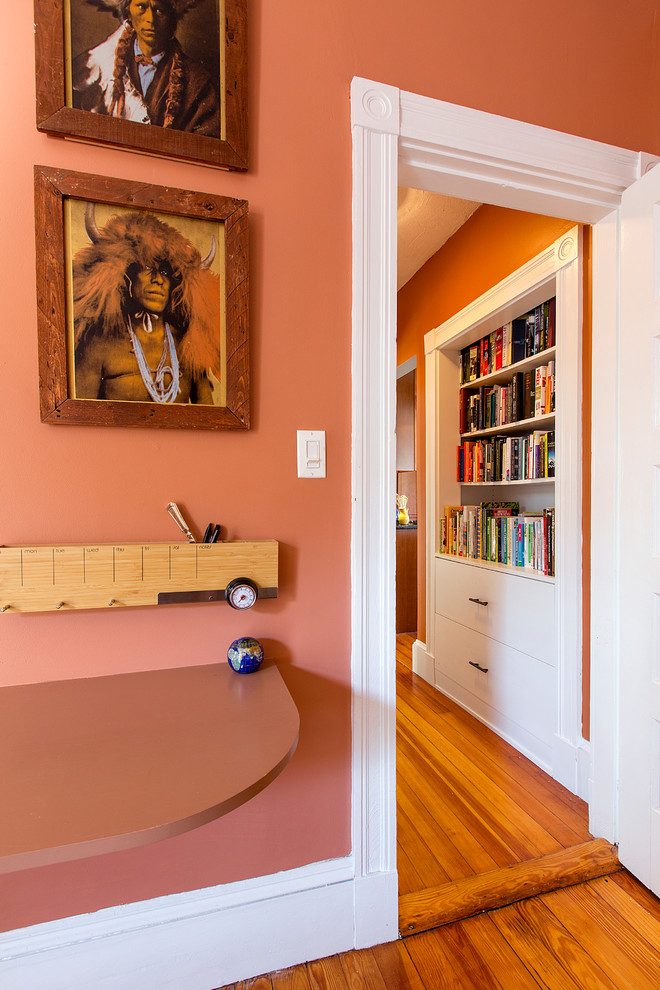 Idee per un piccolo ufficio classico con pareti arancioni, pavimento in legno massello medio, nessun camino, scrivania incassata e pavimento marrone