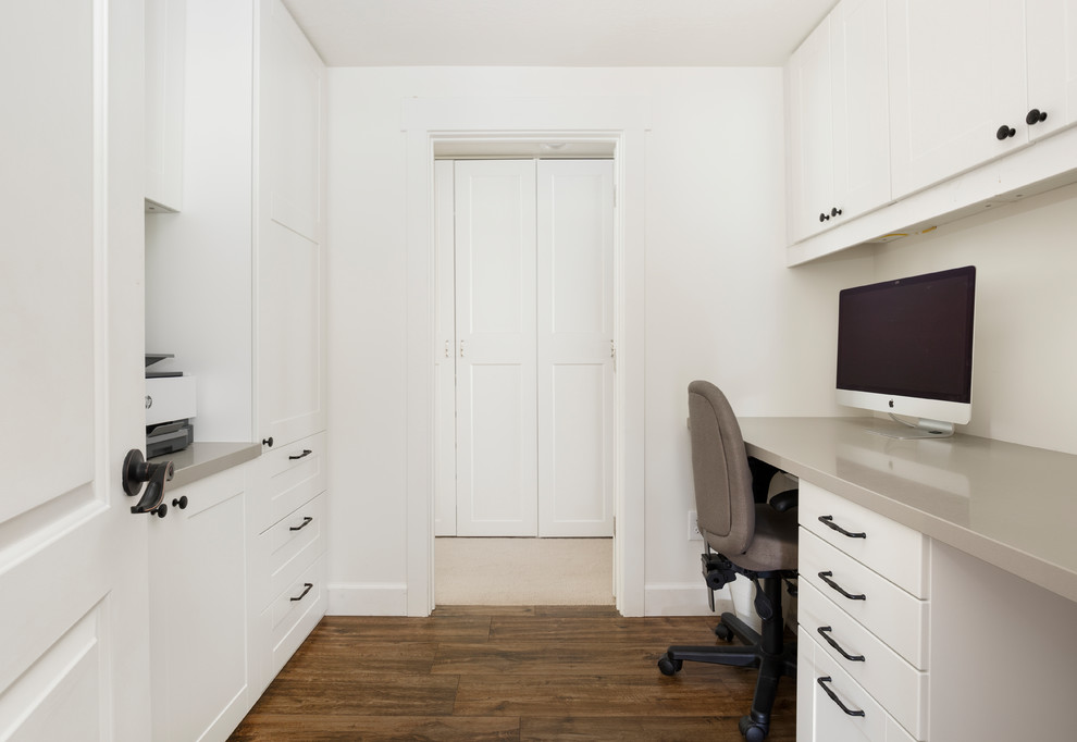 This is an example of a medium sized country craft room in Salt Lake City with white walls, porcelain flooring, a built-in desk and brown floors.