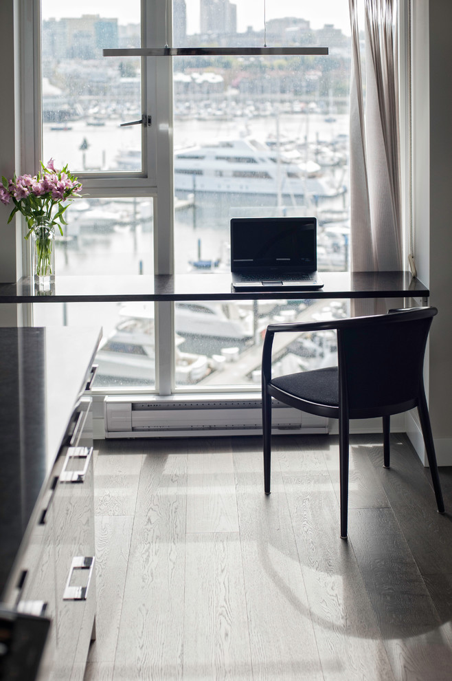 Diseño de despacho actual con suelo de madera en tonos medios y escritorio empotrado