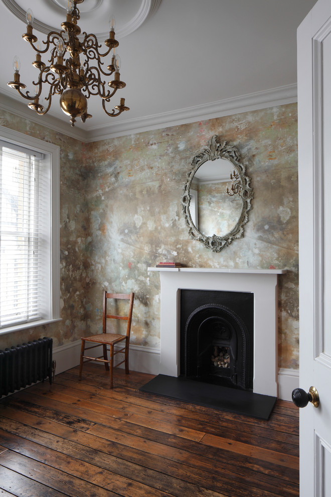 This is an example of a large traditional study in London with multi-coloured walls, dark hardwood flooring, a standard fireplace, a wooden fireplace surround, a freestanding desk, brown floors, a coffered ceiling and wallpapered walls.