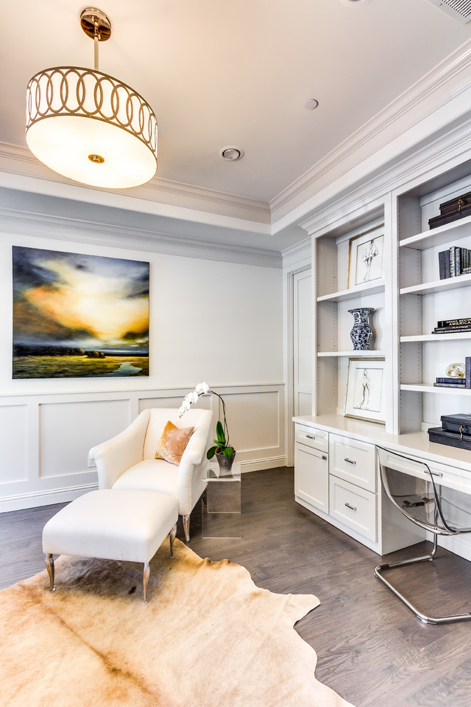 Photo of a classic study in Dallas with white walls, dark hardwood flooring, a built-in desk and brown floors.