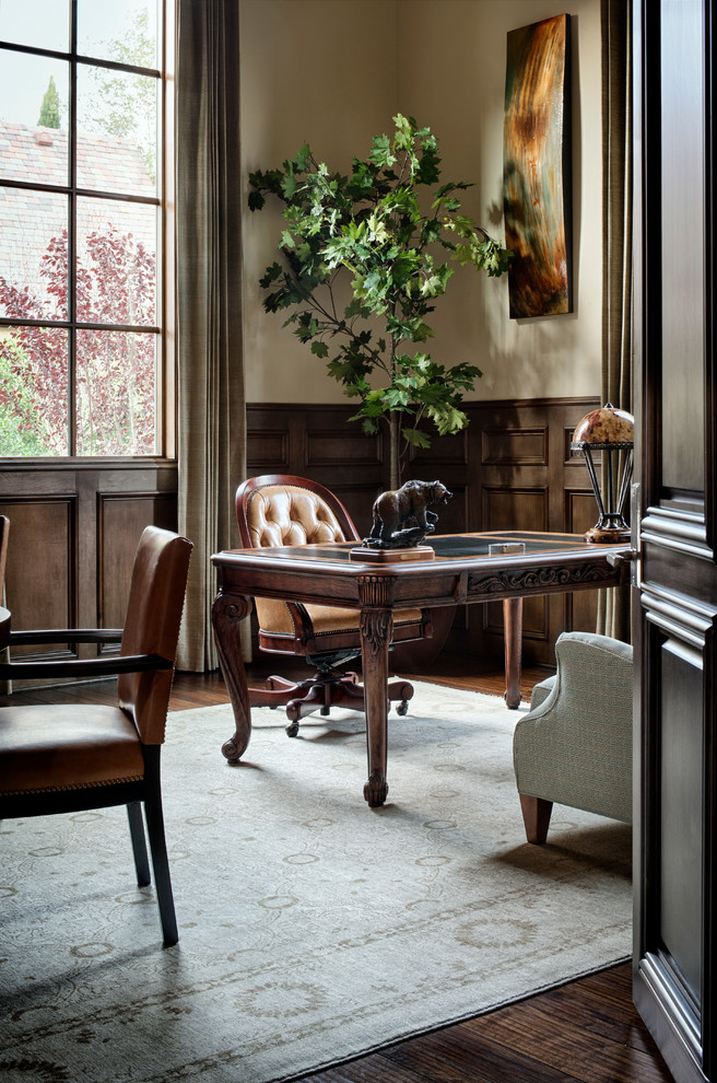 Imagen de despacho clásico con paredes beige, suelo de madera oscura y escritorio independiente