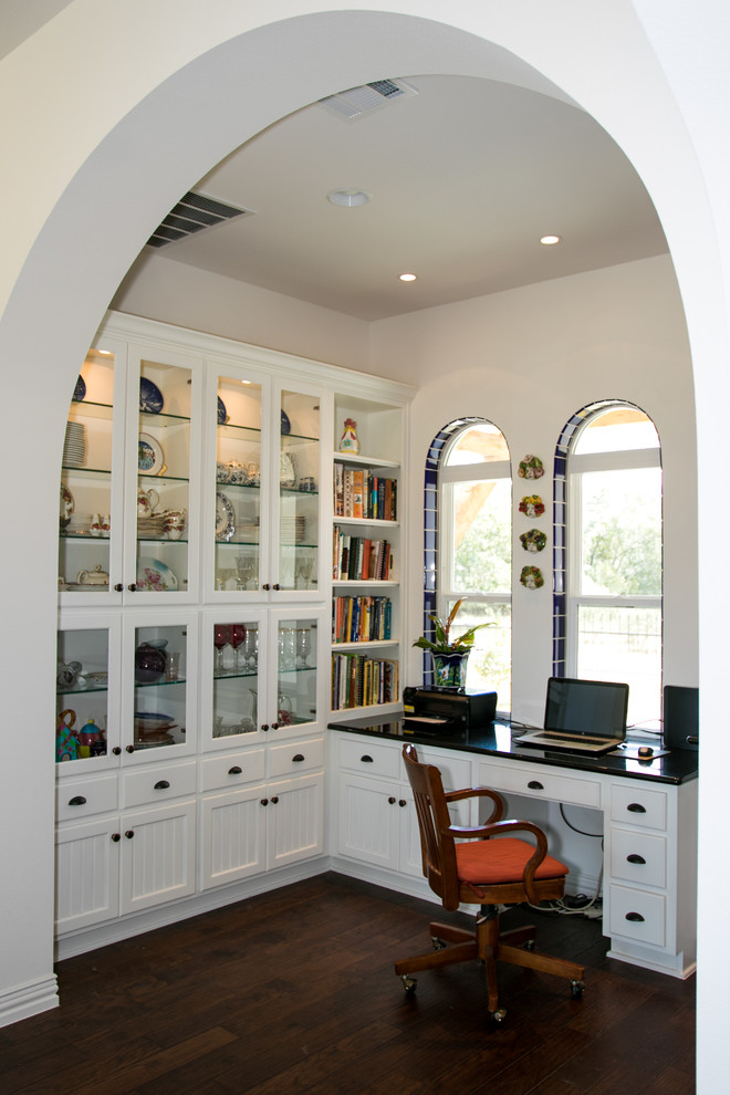 オースティンにある高級な中くらいなサンタフェスタイルのおしゃれな書斎 (ベージュの壁、濃色無垢フローリング、暖炉なし、造り付け机、茶色い床) の写真