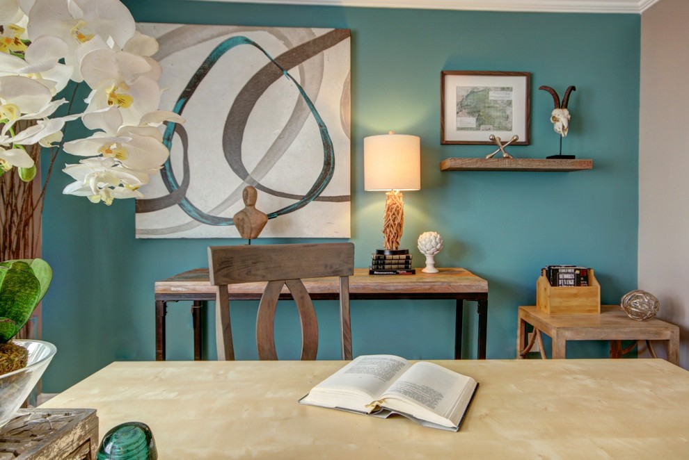 Foto på ett mellanstort eklektiskt hemmabibliotek, med flerfärgade väggar, ett fristående skrivbord och ljust trägolv