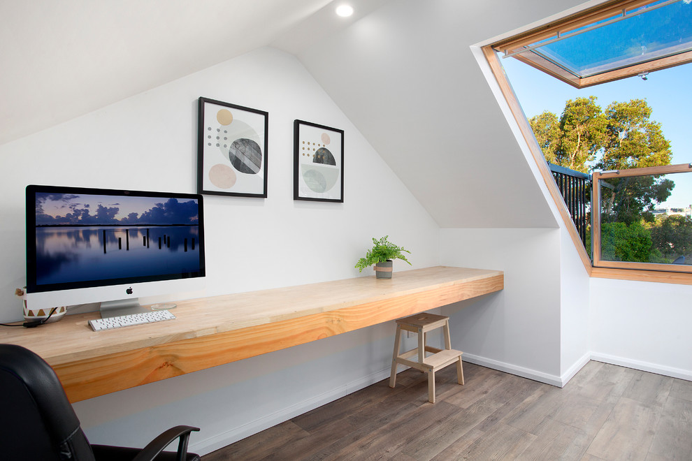 Kleines Modernes Arbeitszimmer ohne Kamin mit Arbeitsplatz, weißer Wandfarbe, Einbau-Schreibtisch, gebeiztem Holzboden und braunem Boden in Sydney