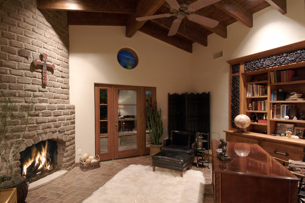 フェニックスにあるお手頃価格の中くらいなサンタフェスタイルのおしゃれな書斎 (テラコッタタイルの床、標準型暖炉、自立型机、ベージュの壁) の写真