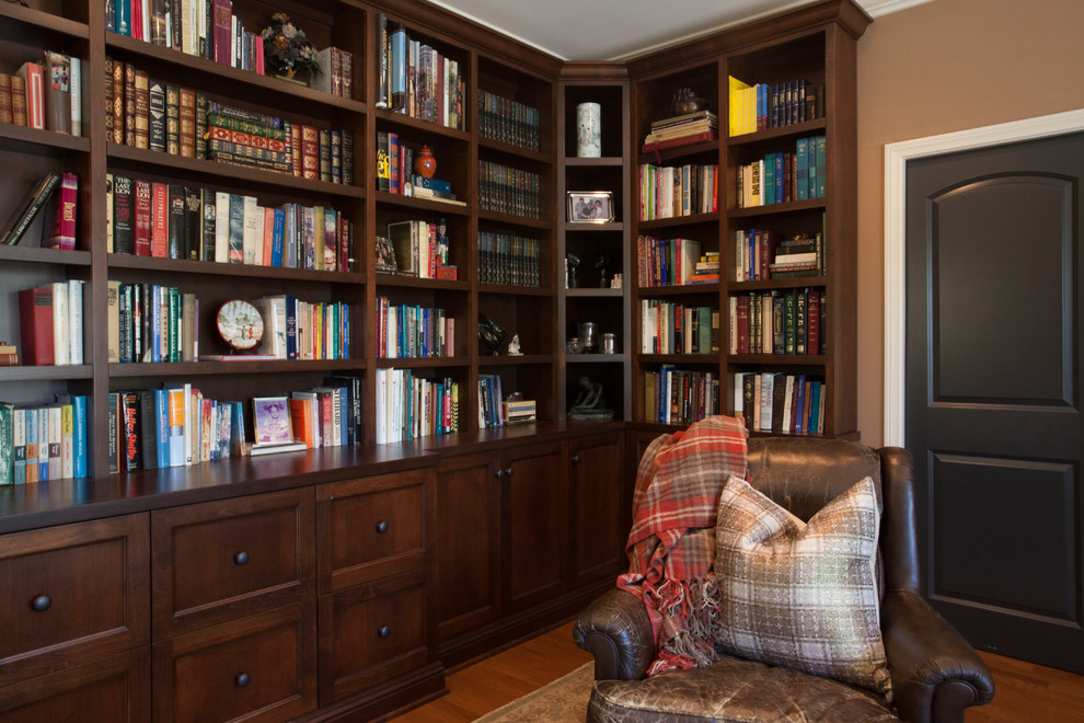 Mittelgroßes Mediterranes Lesezimmer mit brauner Wandfarbe, braunem Holzboden, Kamin, Kaminumrandung aus Stein und braunem Boden in Los Angeles