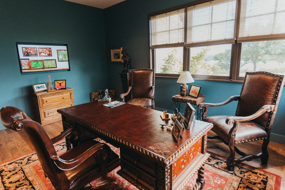 オースティンにあるお手頃価格の小さなサンタフェスタイルのおしゃれな書斎 (青い壁、無垢フローリング、暖炉なし、自立型机、茶色い床) の写真