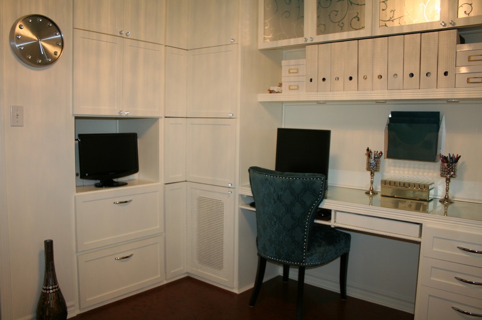 Modelo de despacho contemporáneo pequeño sin chimenea con paredes blancas, suelo de corcho, escritorio empotrado y suelo marrón