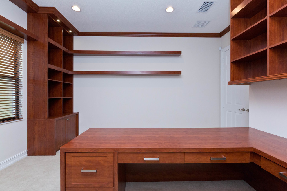 Example of a large built-in desk carpeted home studio design in Miami with white walls